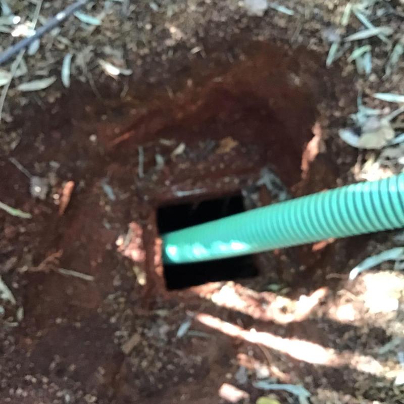 Septic tank inlet with green pipe and chain link fence