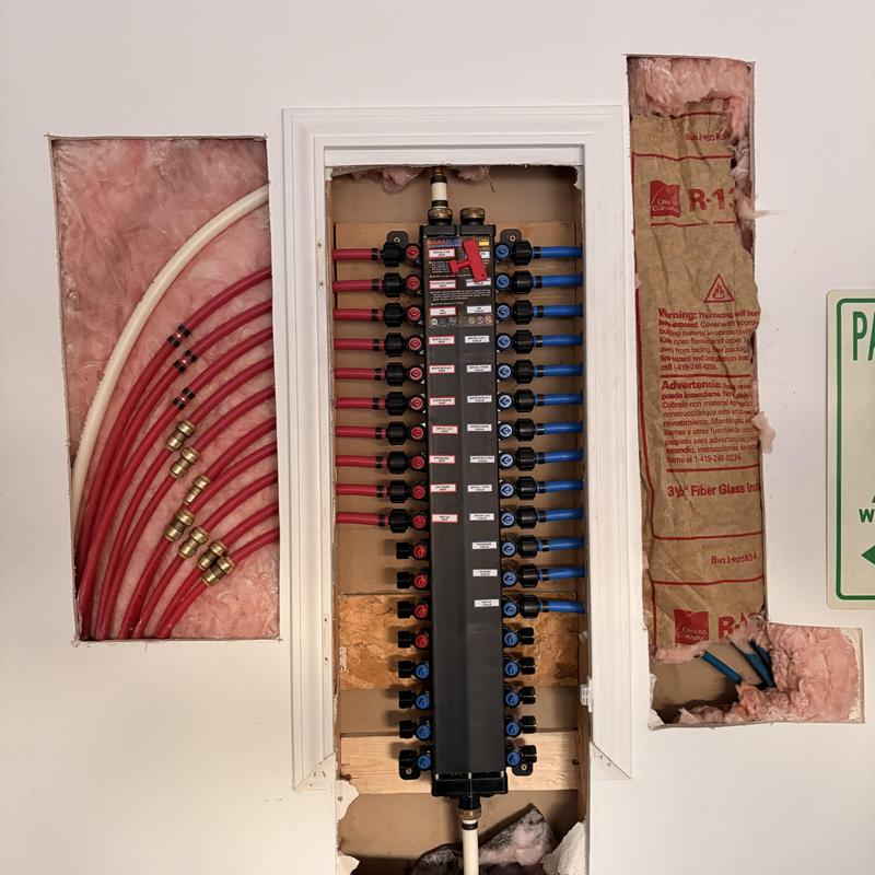 Water manifold with red and blue tubing in garage wall