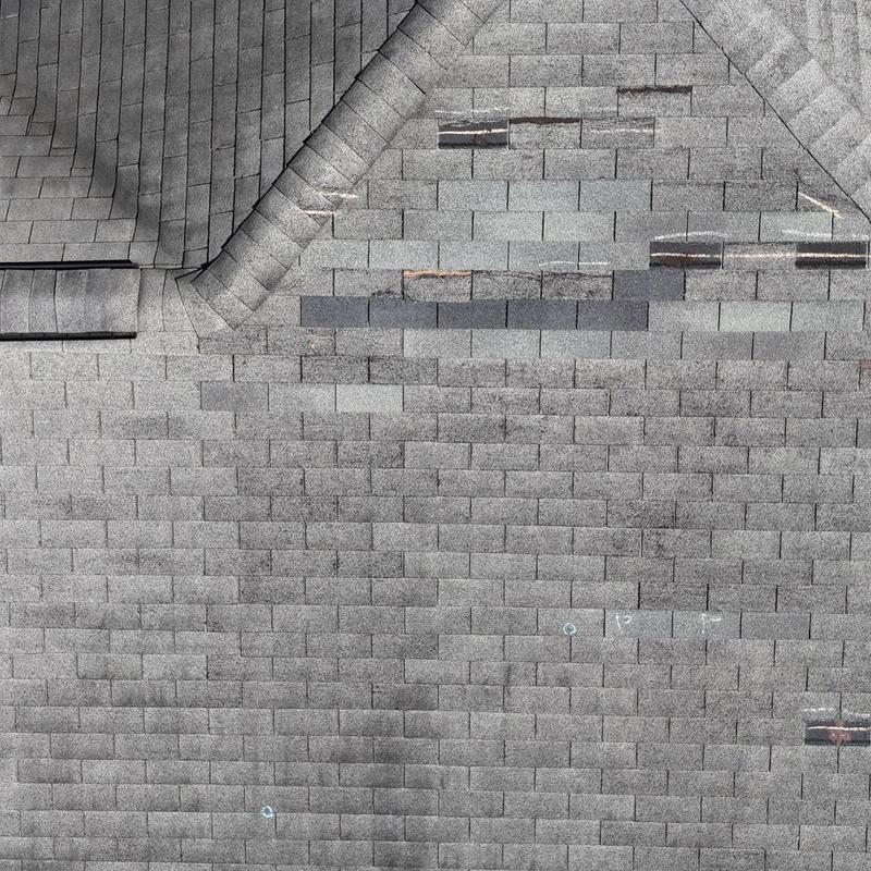 Asphalt shingle roof with marked damaged areas for repair