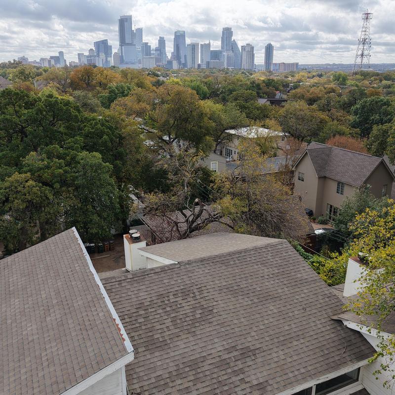 Asphalt shingle roof with Austin city skyline background