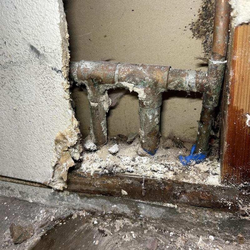Copper water pipe with pinhole leak and drywall damage