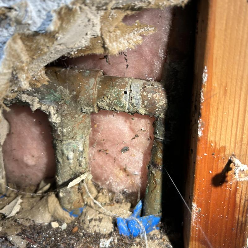 Copper water pipe with pinhole leak in garage wall