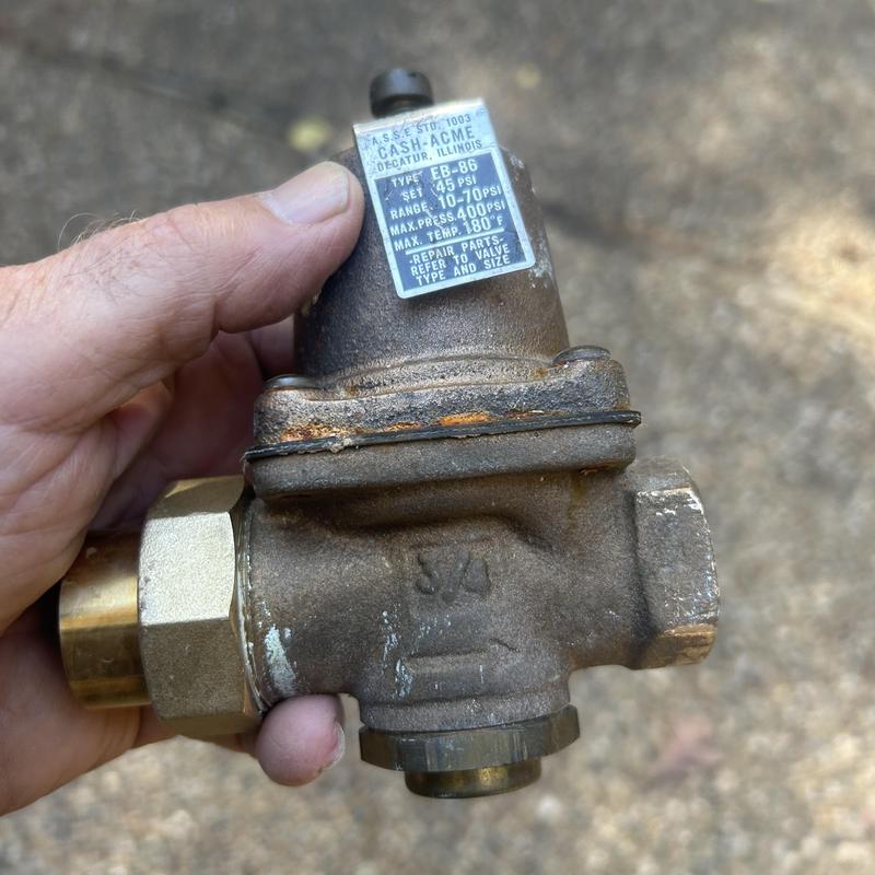 Water pressure regulator valve held by hand outdoors