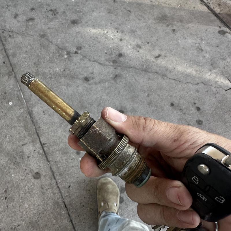 Worn shower stem valve held in hand for replacement