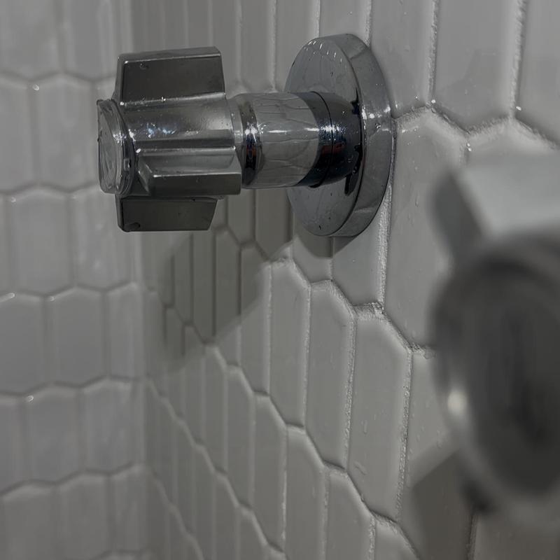Shower valve stem on hex tile wall close-up