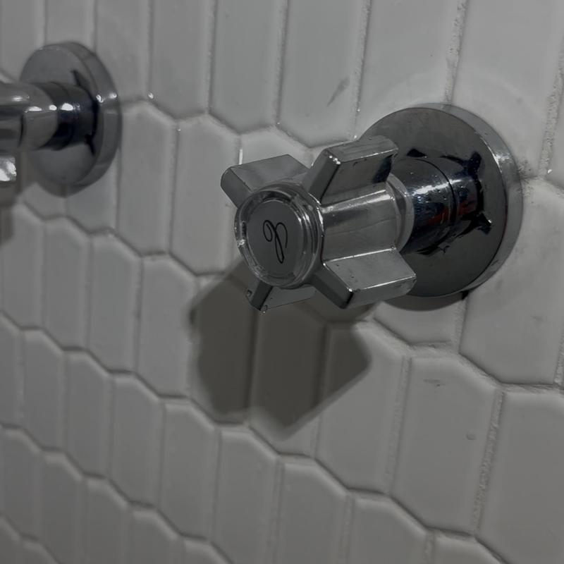Shower valve stem with chrome cross handle on tile wall