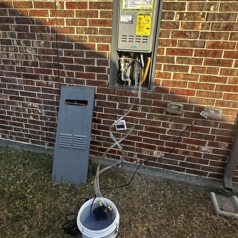Tankless water heater flushing setup outside brick wall