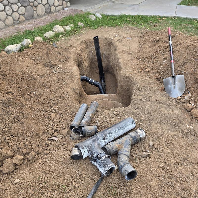 Broken sewer drain line with removed piping and shovel