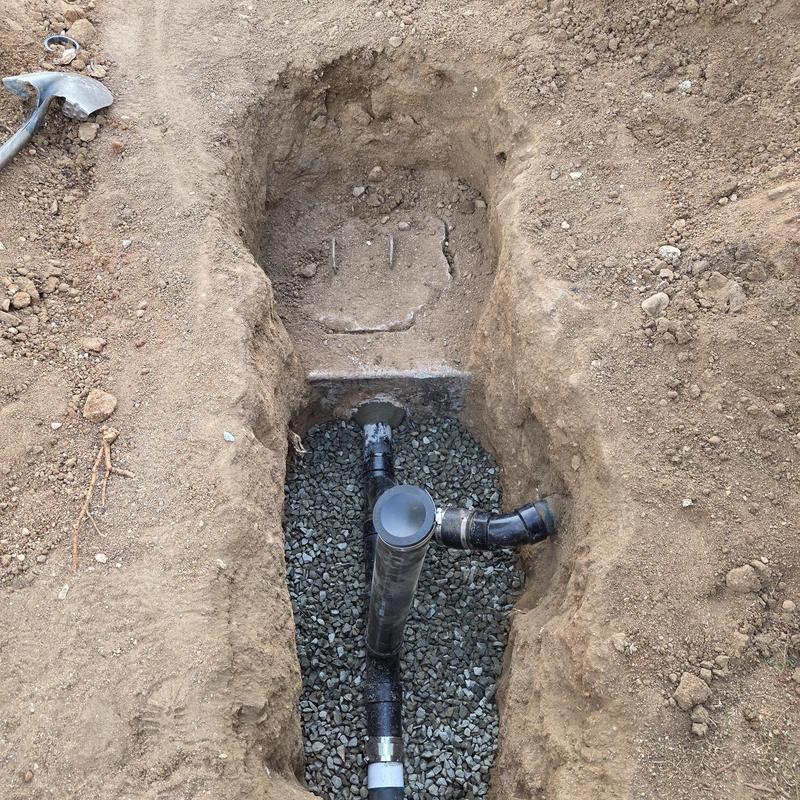 ABS drain pipe installation in dug trench with gravel base