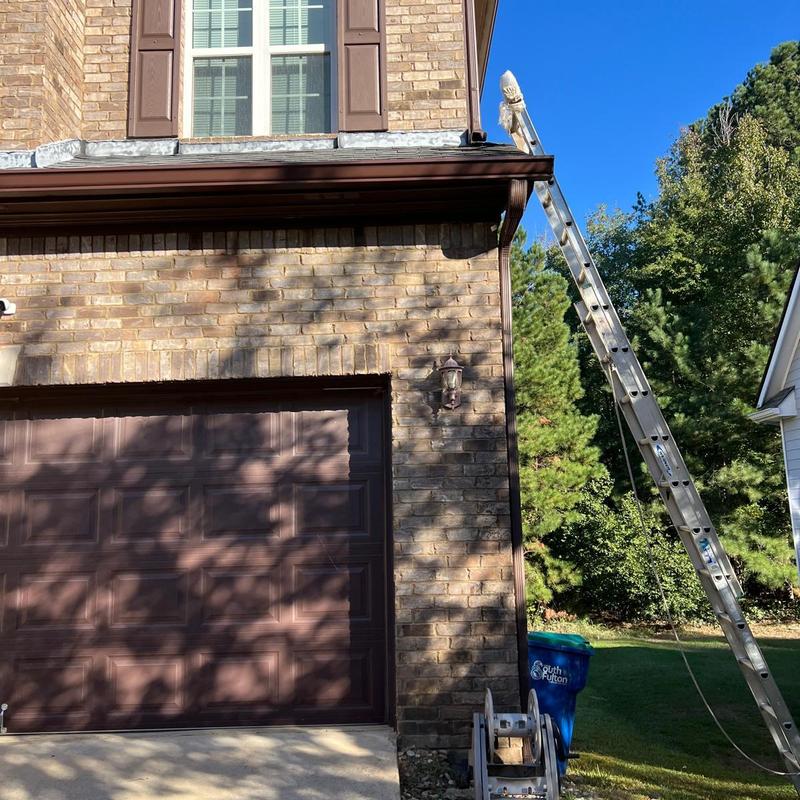 Gutter and downspout system with ladder on house exterior