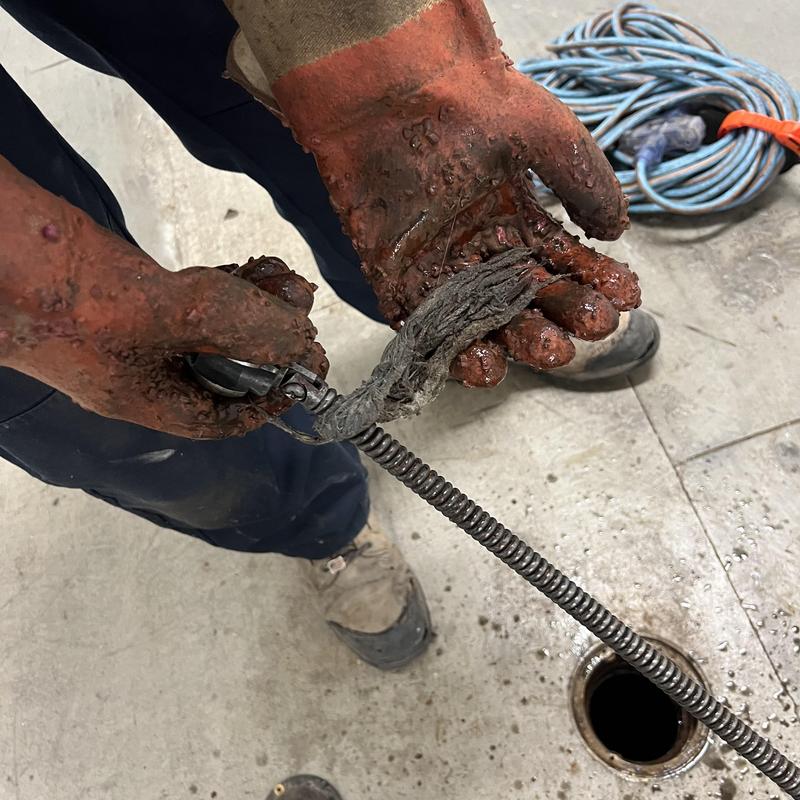 Main drain clog removal with plumbing snake and debris