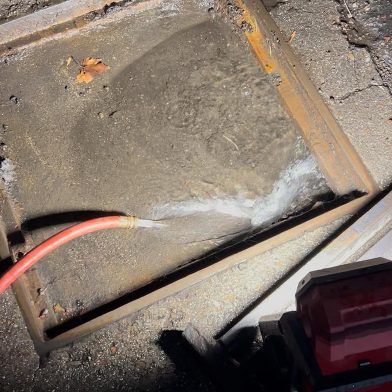 Storm drain cleared with water hose and snake tool