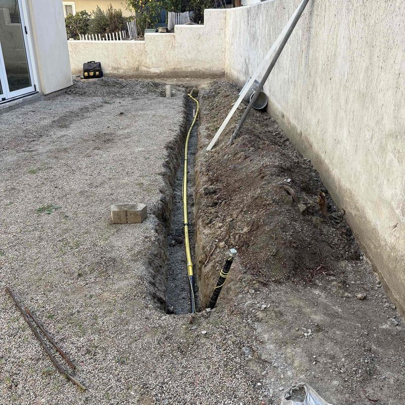 Gas line trench installation beside house wall