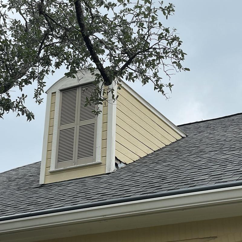 Architectural laminate shingles with wind damage near dormer