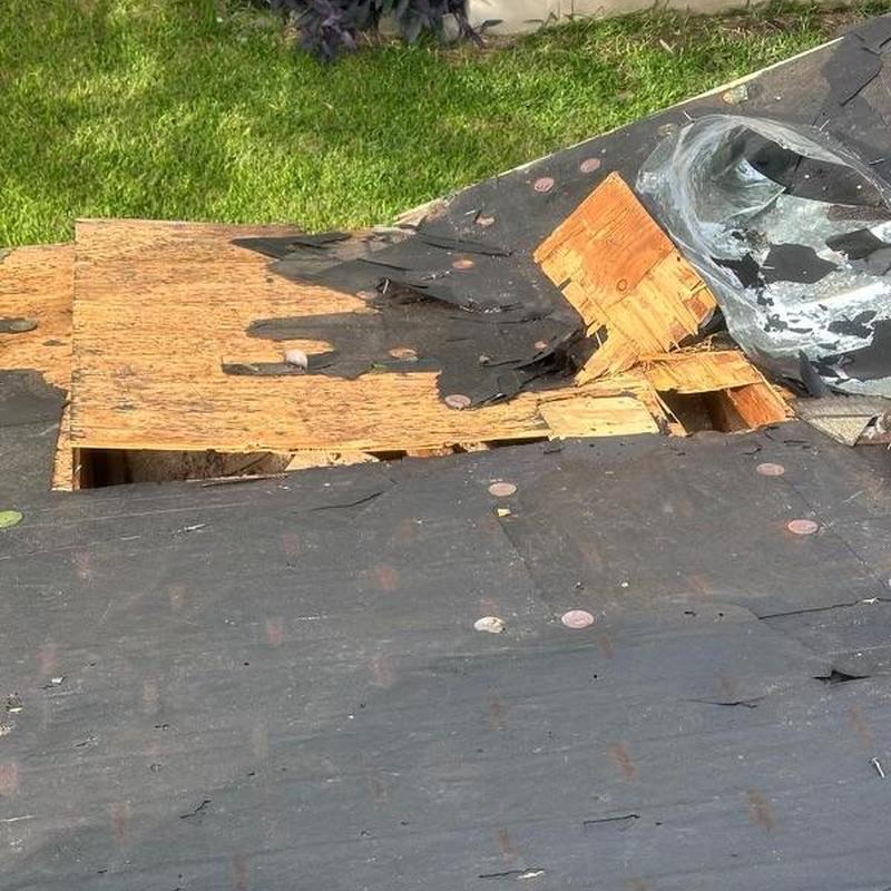 Roof decking exposed with torn underlayment and damaged shingles