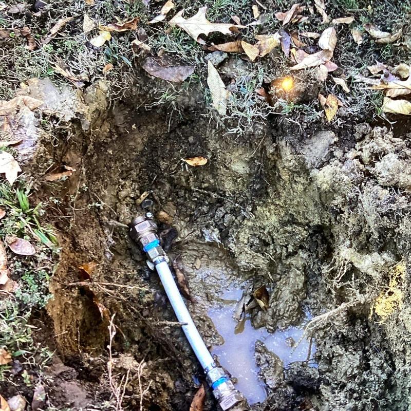 Water meter leak with exposed piping and muddy ground