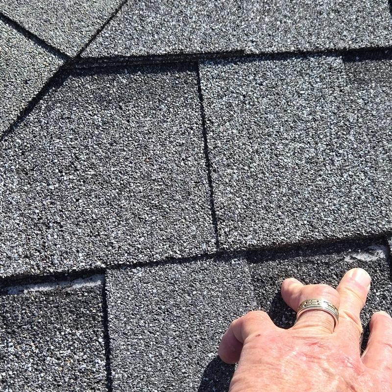Asphalt roof shingles with signs of storm damage inspection
