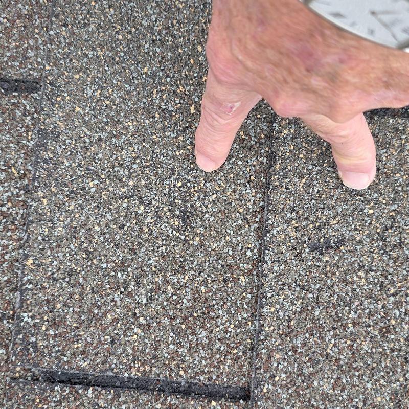 Asphalt shingle damage inspection with finger pointing