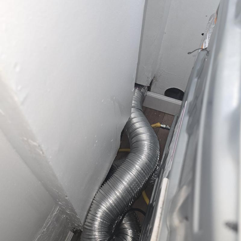 Flexible dryer vent duct behind laundry room appliance