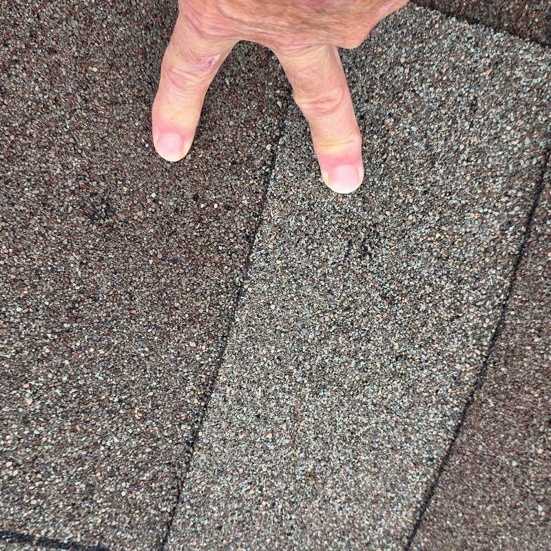 Asphalt roof shingles with hail impact marks visible