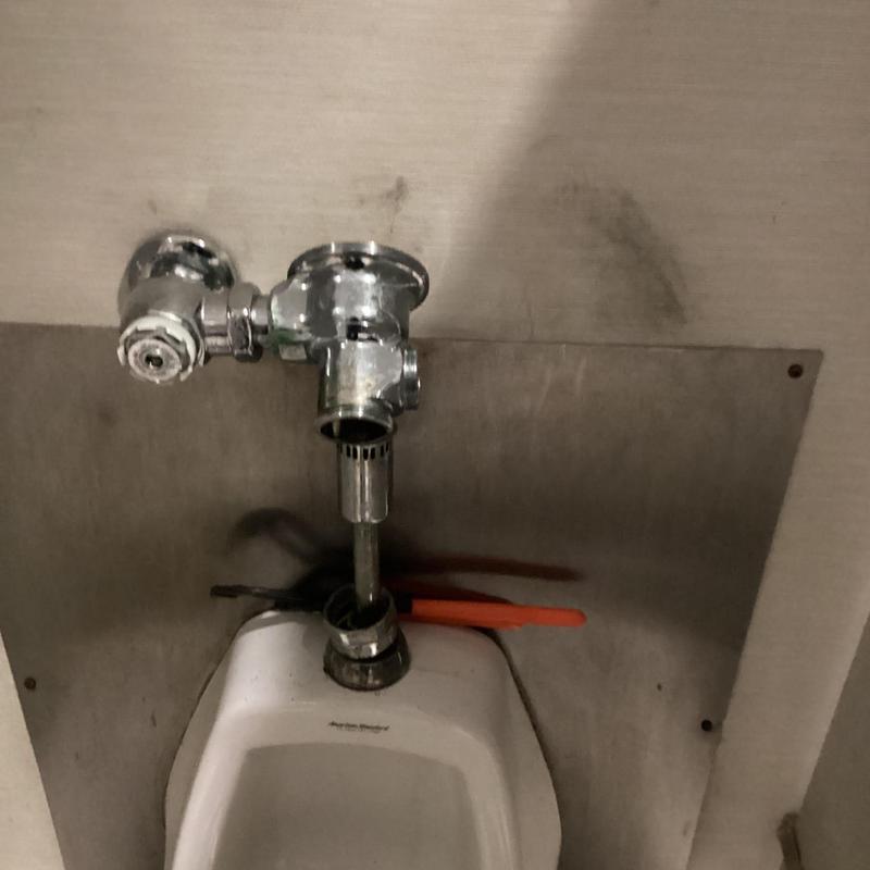 Urinal flush valve with tools against wall