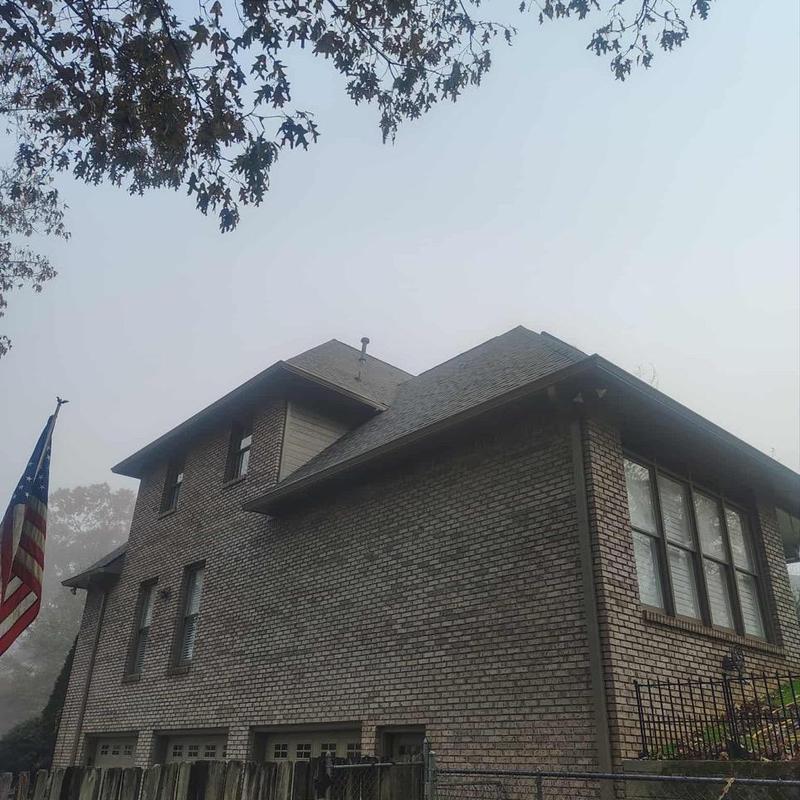 Storm-damaged roof on brick residential home in fog Storm-damaged roof on brick residential home in fog