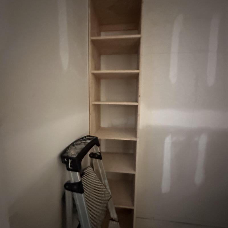 Built-in wooden shelving installation with ladder nearby Built-in wooden shelving installation with ladder nearby