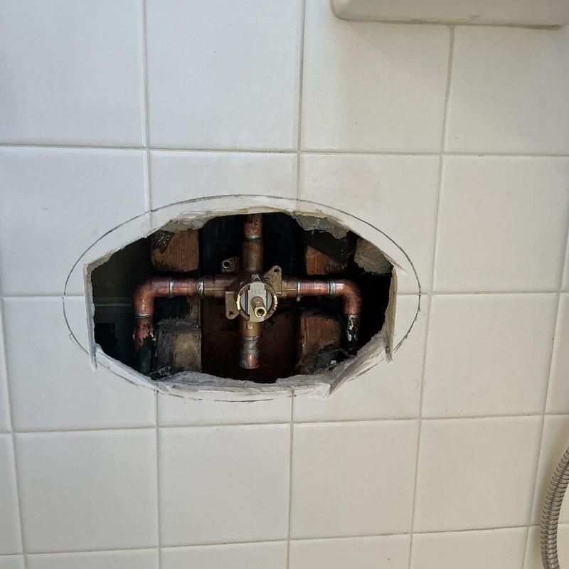 Shower valve plumbing behind tile cutout in wall cavity