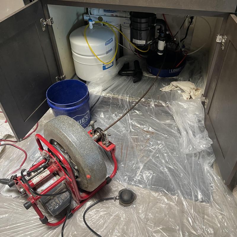 Kitchen sink drain with plumbing snake clearing blockage