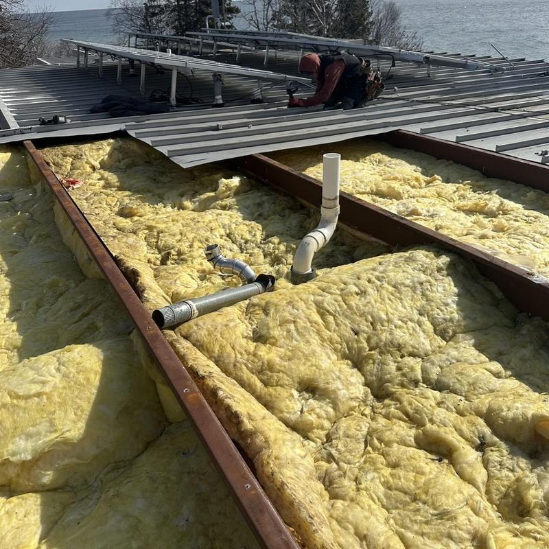 Standing-seam steel roof installation over insulation layers