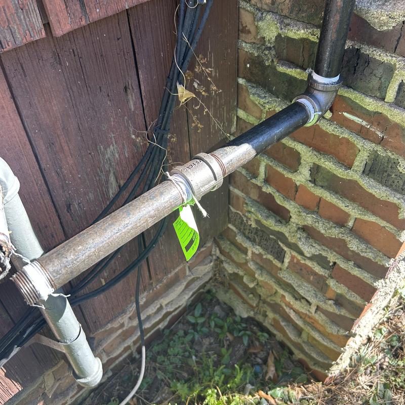 Gas piping with metal fittings on exterior brick wall