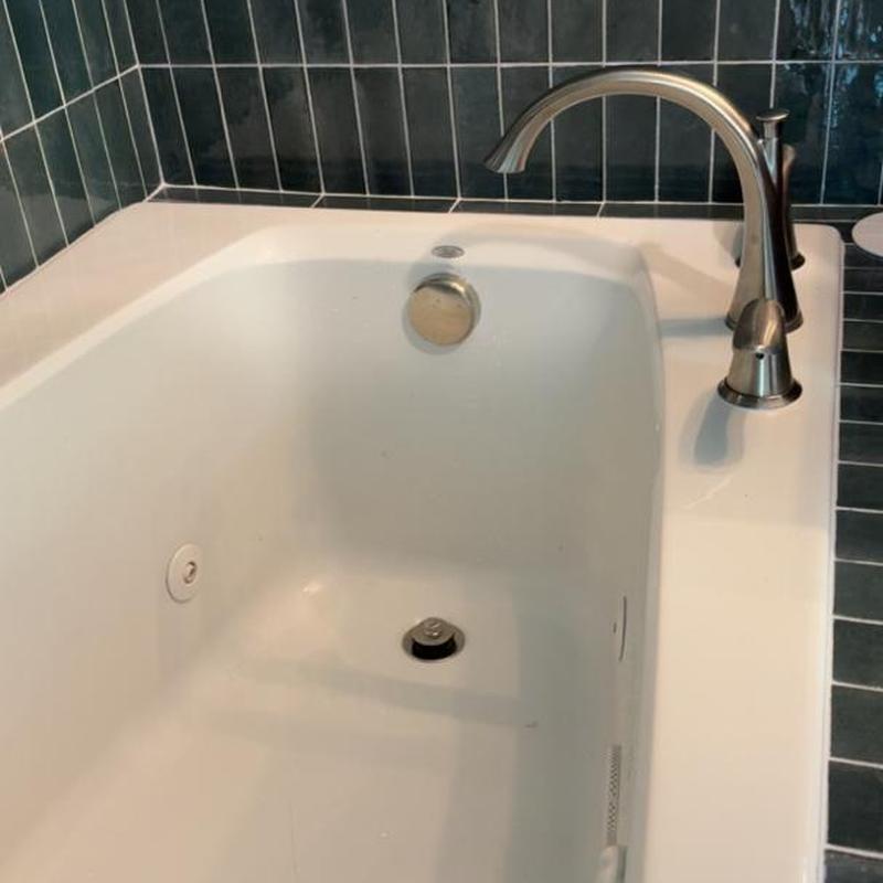 Bathtub faucet and overflow drain installation with tile surround