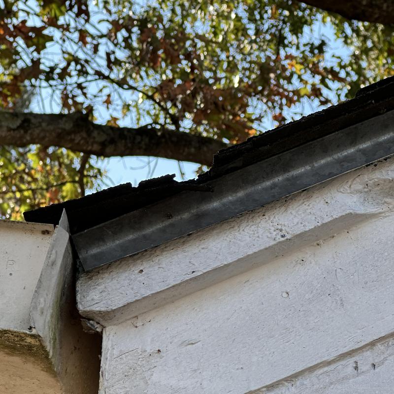 Roof edge metal flashing with damaged shingles
