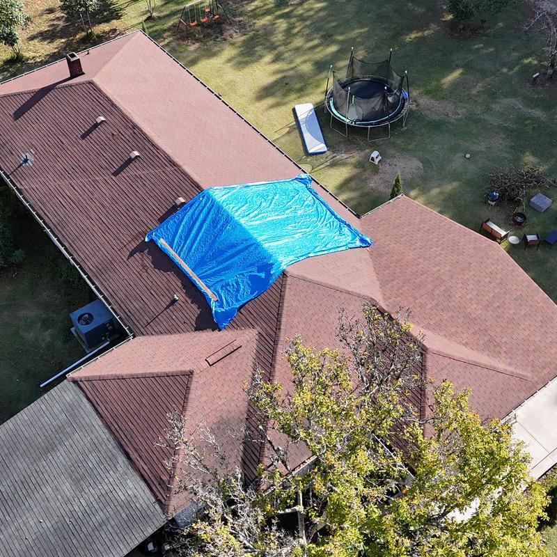 Roof tarping with blue tarp on damaged shingle section