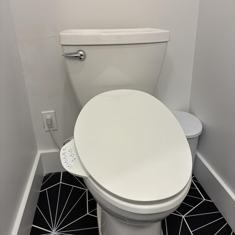 Toilet with bidet seat on black geometric tile floor