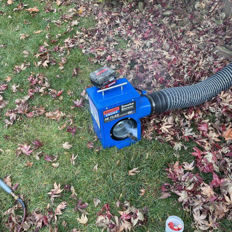 Drainage system smoke blower with hose on grass