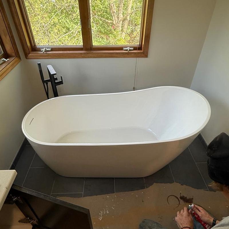 Freestanding bathtub with black floor-mounted faucet