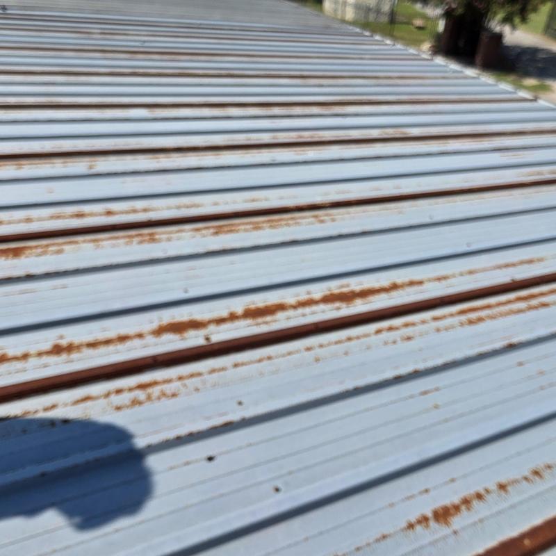 Metal roof panels showing rust and hail damage