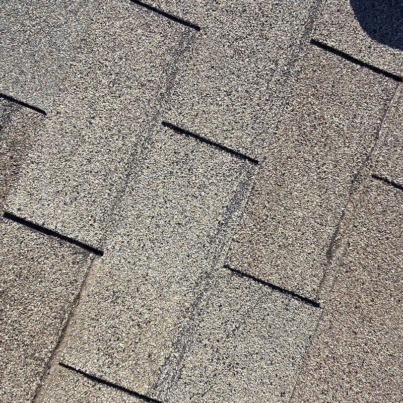Asphalt shingle roof close-up showing granule wear