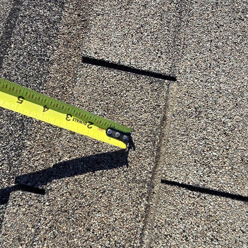 Asphalt shingle cut for leak inspection with tape measure