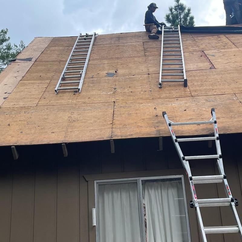Asphalt roof decking replacement with ladders and workers