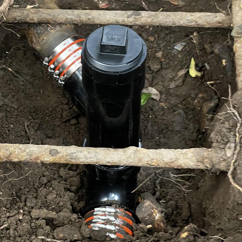 4-inch main drain cleanout with metal clamps in soil