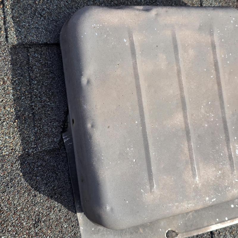 Metal roof vent with hail damage dents on shingles