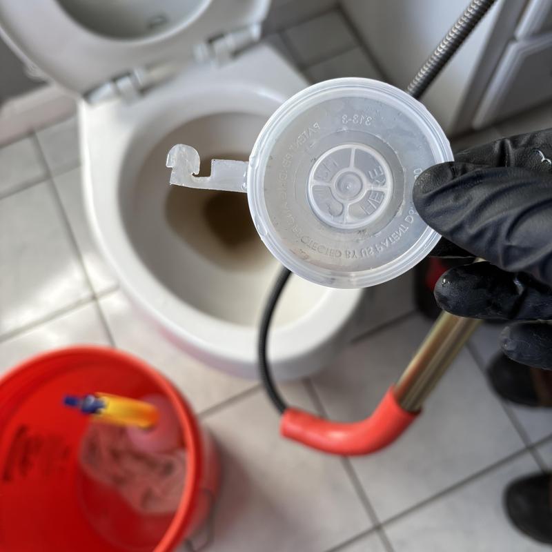Toilet lid retrieval with plumbing auger near bowl