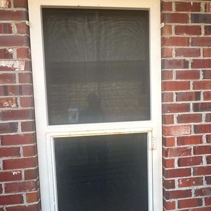 Screen door frame rust inspection on brick wall