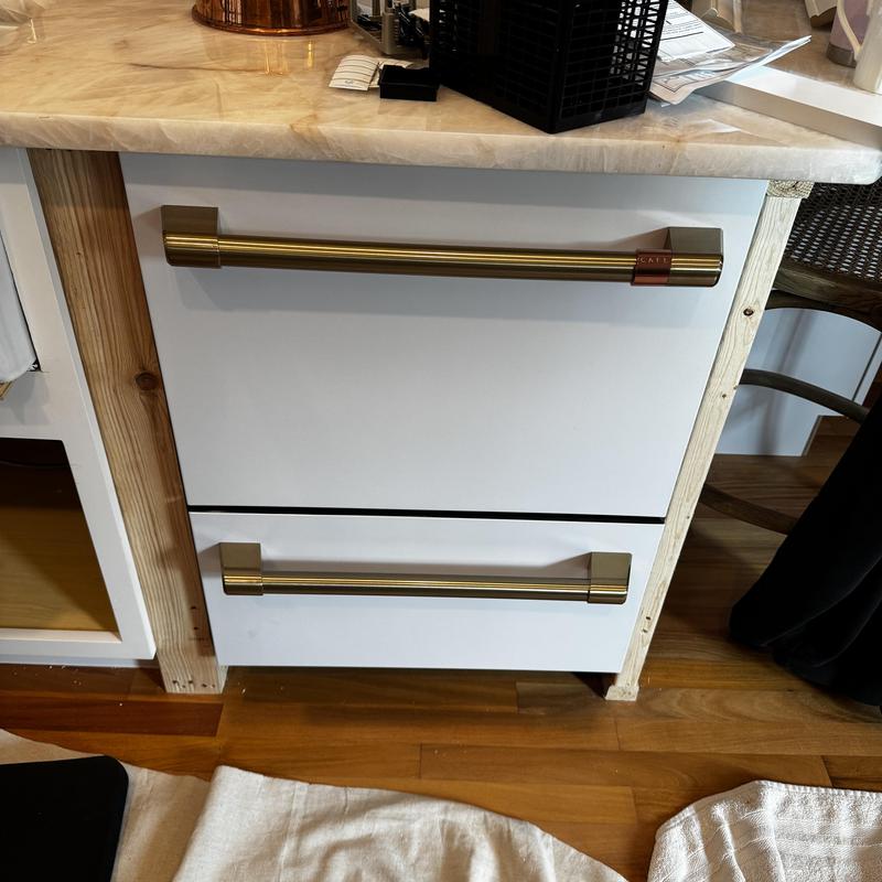 Dishwasher installation with gold handles under countertop