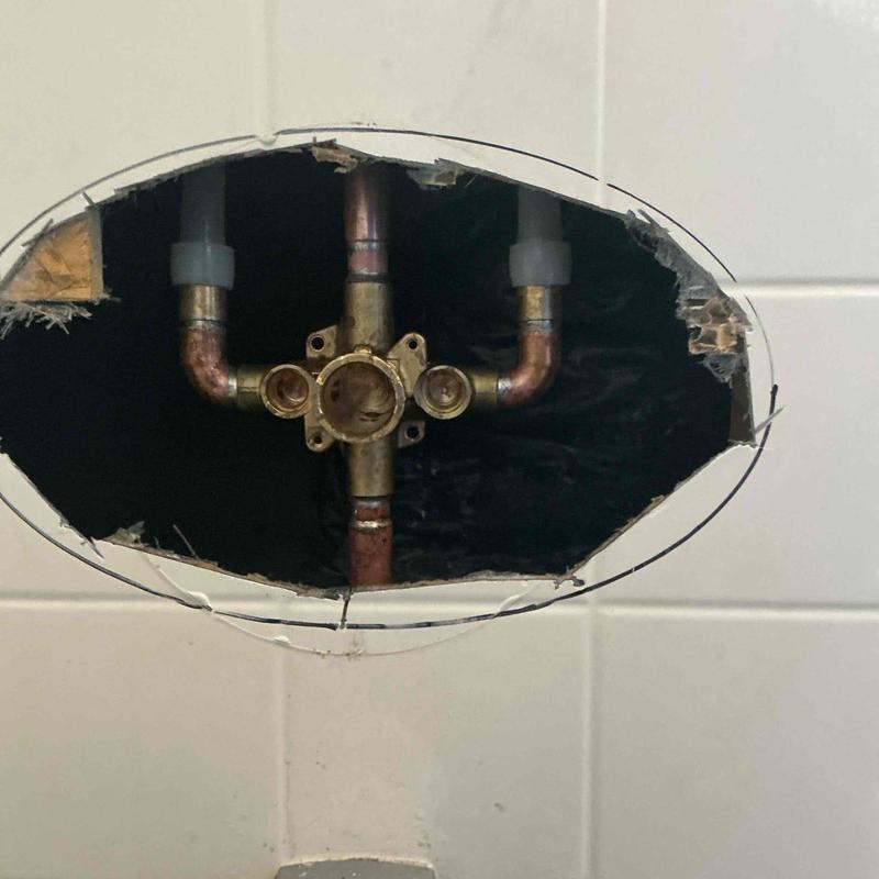 Delta shower valve plumbing behind bathroom tile wall opening