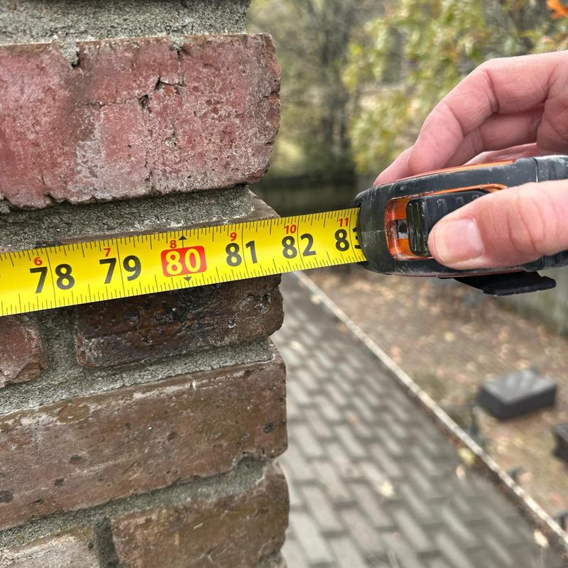 Brick chimney measurement with tape during roof inspection