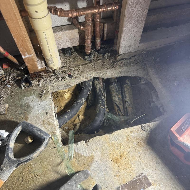 Concrete foundation with exposed water pipes and leak hole Concrete foundation with exposed water pipes and leak hole