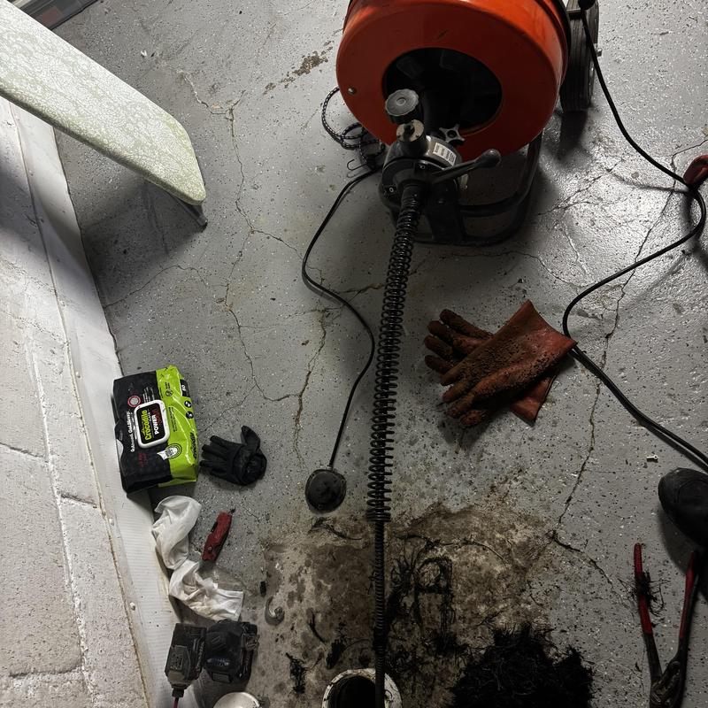 Drain snake machine and gloves on floor during plumbing job